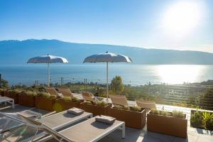 une terrasse avec des chaises et des parasols et l'océan dans l'établissement Relais Zenner, à Toscolano Maderno