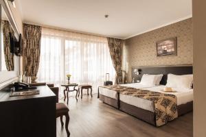 a hotel room with a large bed and a table at Hotel & SPA Diamant Residence - All Inclusive in Sunny Beach