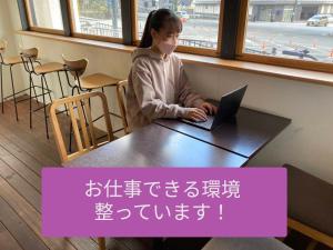 una ragazza seduta a un tavolo con un portatile di Santiago Guesthouse Kyoto a Kyoto