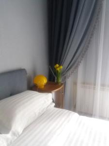 1 dormitorio con 1 cama y un jarrón con flores amarillas en Apartment u Lidii in center of Kiev near railways station, en Kiev