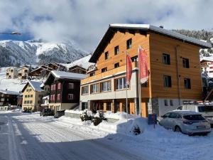 een groot houten gebouw met vlaggen in de sneeuw bij Mountain Lodge Sedrun in Sedrun