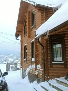 a log cabin with snow on the side of it at Вілла Олекси in Skhidnitsa