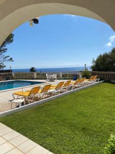 une piscine avec des chaises et l'océan en arrière-plan dans l'établissement Villa Can Pere Cala Galdana Menorca, à Cala Galdana