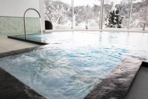 a jacuzzi tub in a room with snow at Hotel Waldegg - Adults only in Engelberg