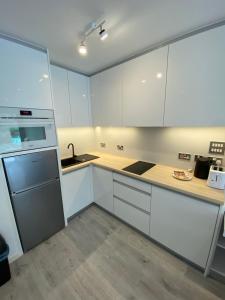 a kitchen with white cabinets and a sink at Modern Studio Apartment at The Hub in Gibraltar