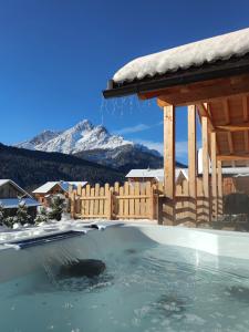 een hot tub met een houten hek en met sneeuw bedekte bergen bij Alpenchalets Mair in Sesto