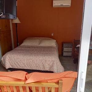 een kleine slaapkamer met een bed en een televisie bij Monoambiente en Colonia in Colonia del Sacramento