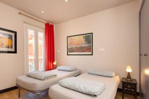 2 camas individuais num quarto com cortinas vermelhas em Villa Saint Exupery Beach Hostel em Nice