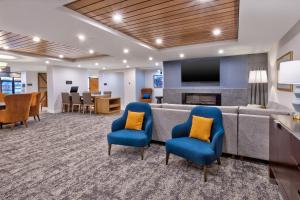 uma sala de espera com um sofá e cadeiras e uma televisão em Staybridge Suites Pittsburgh Airport, an IHG Hotel em Pittsburgh