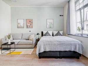 a white bedroom with a bed and a couch at limehome Leipzig Oelßner's Hof in Leipzig