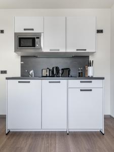 a white kitchen with white cabinets and a microwave at limehome Leipzig Oelßner's Hof in Leipzig