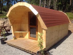 une petite cabane en bois avec un toit marron dans l'établissement Camping Pod Heaven, à Brackla