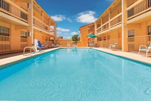 - une grande piscine dans un hôtel avec des chaises et des parasols dans l'établissement Baymont by Wyndham Lubbock - Downtown Civic Center, à Lubbock