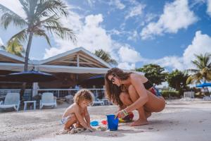 a woman and a child playing in the sand on the beach at Siboney Beach Club in Saint Johnʼs