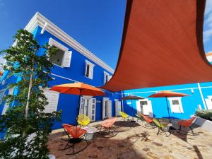 un bâtiment bleu avec des chaises et des parasols devant lui dans l'établissement The Freedom Hotel, à Willemstad