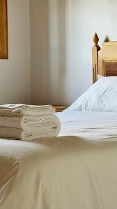 a bed with white sheets and a wooden head board at Casa do Rio Alva in Arganil