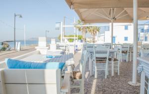 un restaurant avec des tables et des chaises blanches et l'océan dans l'établissement Laza Beach, à Skala