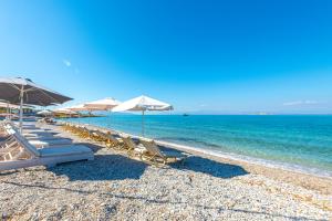 - un groupe de chaises longues et de parasols sur une plage dans l'établissement Laza Beach, à Skala