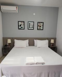 1 dormitorio con 1 cama blanca y 2 toallas en Shellter Hotel, en Holambra