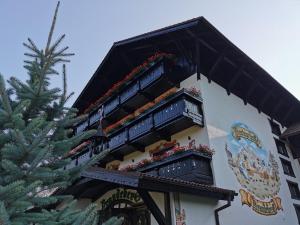 um edifício com varandas com flores ao lado de uma árvore de Natal em Brandeberg Pension & Restaurant em Bran