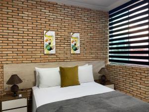 um quarto com uma cama branca e uma parede de tijolos em B & A Suites Inn Flats - Apart Flat Stratus em Anápolis