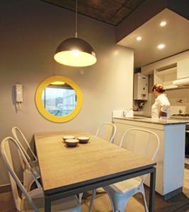 a dining room with a table and a woman in a kitchen at Naranjo 9A in San Salvador de Jujuy