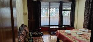 een slaapkamer met een bed en een raam met gordijnen bij The River View Homestay in Kurseong