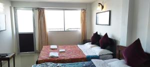 een hotelkamer met een bed en twee ramen bij The River View Homestay in Kurseong