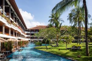 a resort with a swimming pool and palm trees at Meliá Bali in Nusa Dua