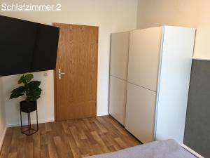 Cette chambre dispose d'un réfrigérateur blanc et d'une porte. dans l'établissement Ferienwohnung RIENA, à Riesa