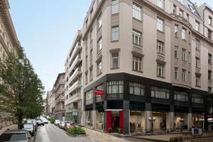 een hoog gebouw in een stadsstraat met auto's geparkeerd bij Ramada by Wyndham Budapest City Center in Boedapest