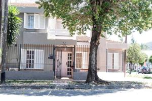 ein weißes Haus mit einem Tor und einem Baum in der Unterkunft Casa boutique, cerca de la Virgen del Cerro en SALTA in Salta