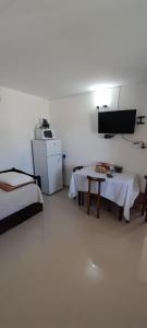 Cette chambre comprend deux lits, une table et un réfrigérateur. dans l'établissement Apartamento Familiar Marta, à Colonia del Sacramento