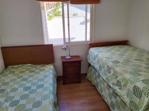 a bedroom with two beds and a table with a window at Casas Isla Negra in El Quisco