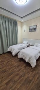 Duas camas num quarto com pisos em madeira em HAVANA HOLIDAY HOMES MIRDIF no Dubai