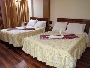 two beds with swans on them in a hotel room at Hostal Mirador Korichaska in Puno