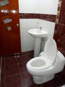 a bathroom with a white toilet and a sink at Hostal Mirador Korichaska in Puno