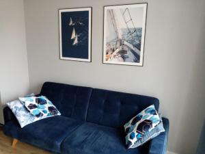 eine blaue Couch in einem Wohnzimmer mit zwei Bildern in der Unterkunft Family & Business Elegant Apartments Wspólna Centrum Downtown - 1 Bedroom, Terrace, Air Conditioning, Garage, NEW! in Kielce