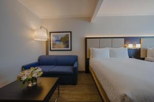 a hotel room with a bed and a blue chair at Holiday Inn Express & Suites Santa Clara - Silicon Valley, an IHG Hotel in Santa Clara