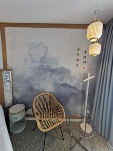 Cette chambre comprend une chaise et un mur orné d'une fresque murale représentant les nuages. dans l'établissement Hotel Zhong Hua, à Sopot