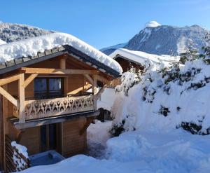 een blokhut met een balkon in de sneeuw bij Chalet Delphinette - Spa privatif in Morzine