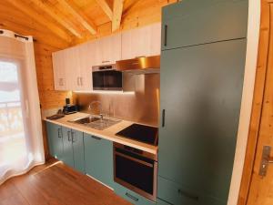 een keuken met een roestvrijstalen koelkast en een wastafel bij Chalet Delphinette - Spa privatif in Morzine