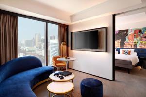 Habitación de hotel con sofá azul y TV en ibis Styles Jakarta Tanah Abang, en Yakarta