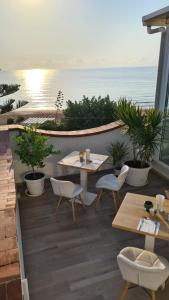 een patio met tafels en stoelen en de oceaan bij Pantanello Rooms Avola in Avola