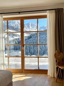 een slaapkamer met een groot raam met uitzicht op de bergen bij Surrounded by green - Luxury Chalet at the foot of the Dolomites in La Villa