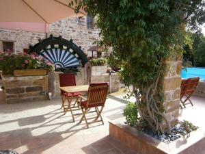 d'une terrasse avec une table, des chaises et un arbre. dans l'établissement Mouzaliko Guesthouse Mansion, à Kambos