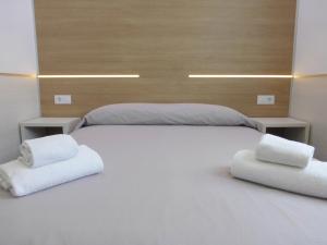 1 cama blanca grande con 2 toallas blancas. en Rentalmar Navarra family suites, en Salou