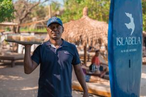 um homem segurando um tabuleiro de comida na frente de uma prancha de surf em Hotel Islabela Islas Del Rosario em Isla Grande