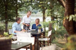 um grupo de pessoas sentadas em torno de uma mesa em um jardim em Van der Valk Hotel Gilze-Tilburg em Tilburgo