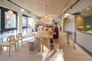 Una donna seduta a un tavolo di legno in un ristorante di Hôtel Life Bordeaux Gare - BG a Bordeaux